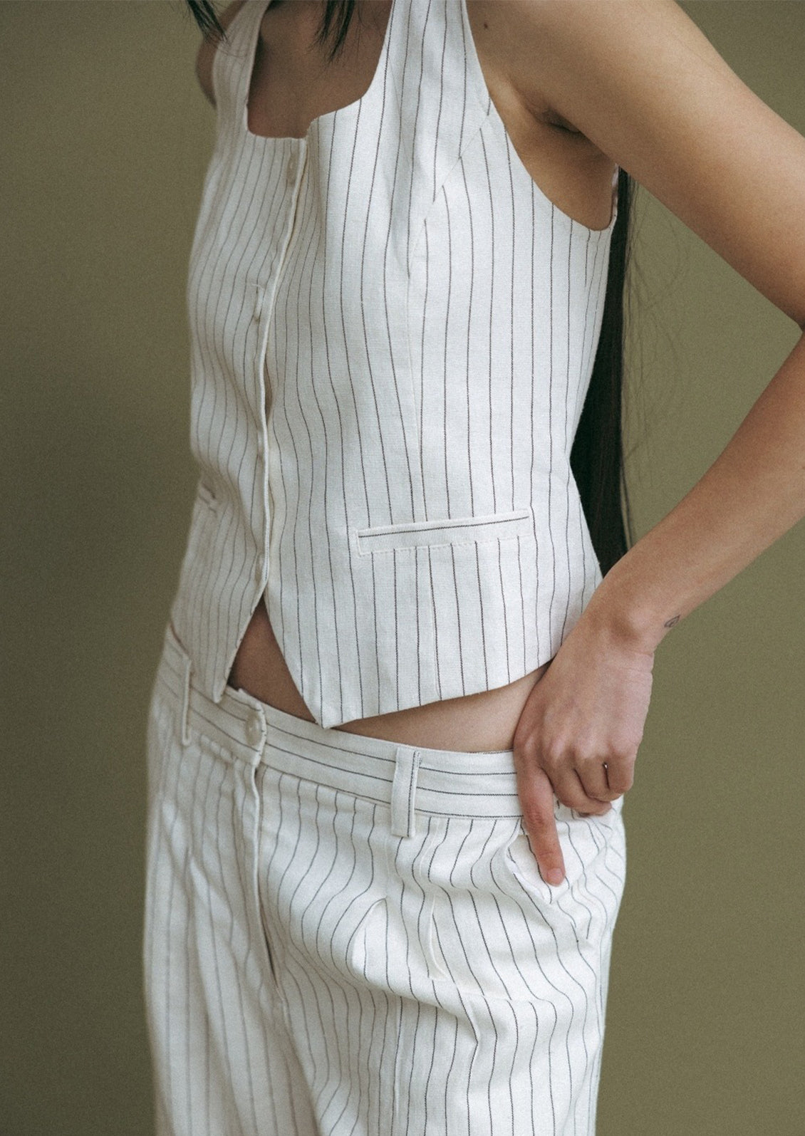 A woman wearing a white baseball style vest with black pinstripe.