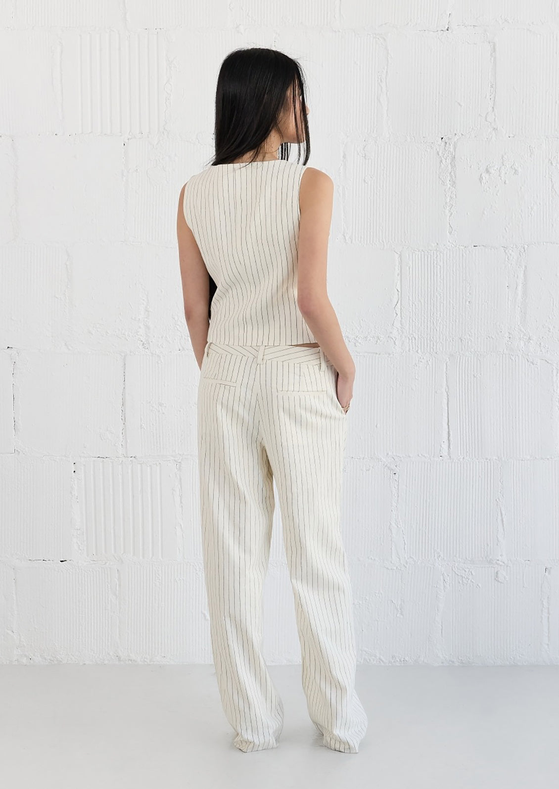 A woman wearing a white baseball style vest with black pinstripe.