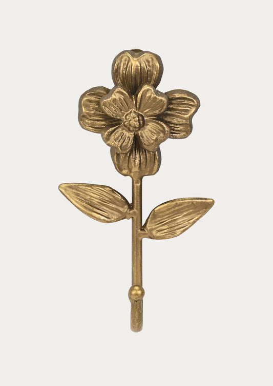 A handcrafted cast iron wall hook in the shape of a flower in a gold finish on a white background.