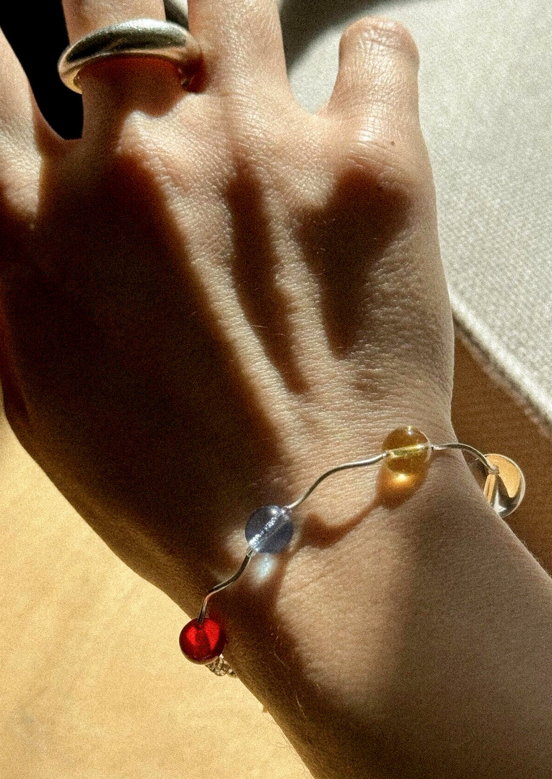 A sterling silver bracelet with a variety of different beads on a woman's wrist.