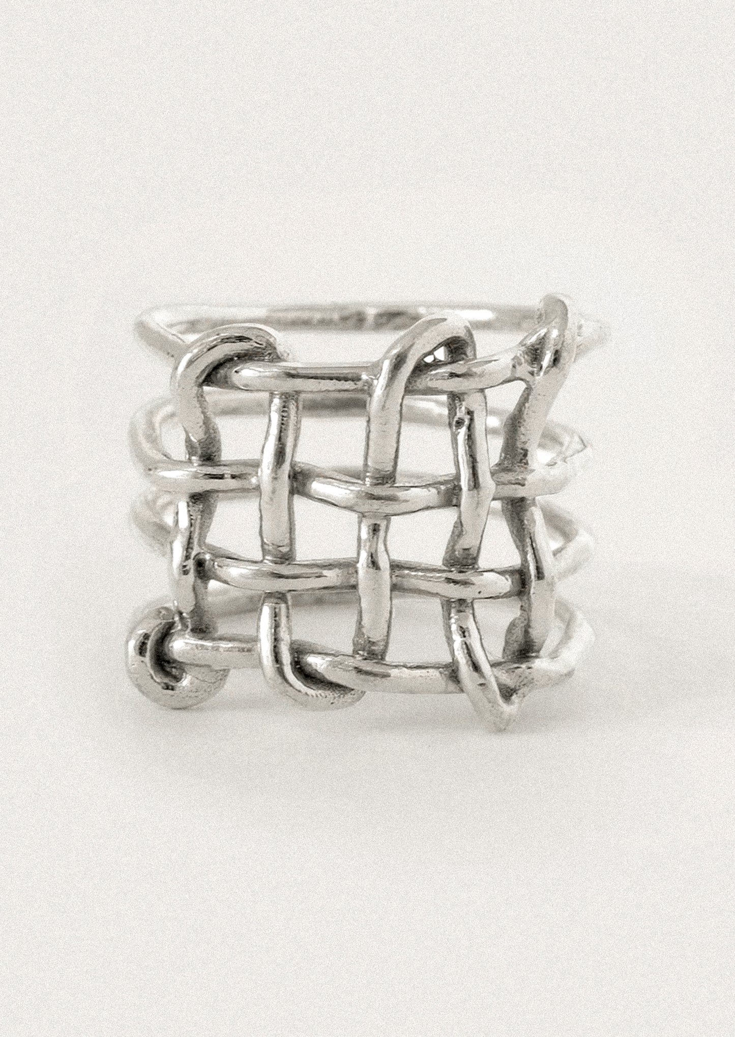 A silver ring with a textured, interlocking chain-link or woven basket-like design.