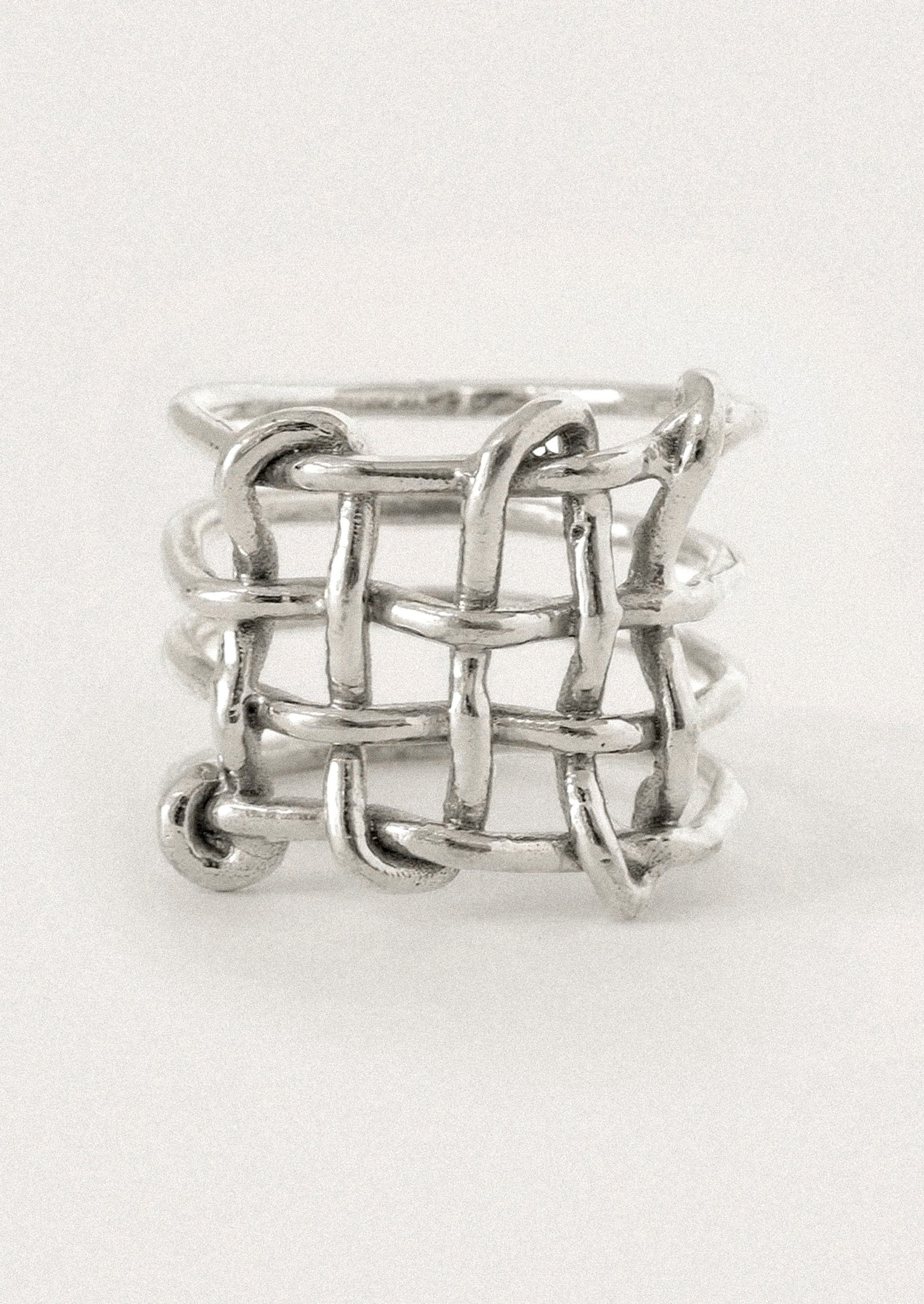 A silver ring with a textured, interlocking chain-link or woven basket-like design.