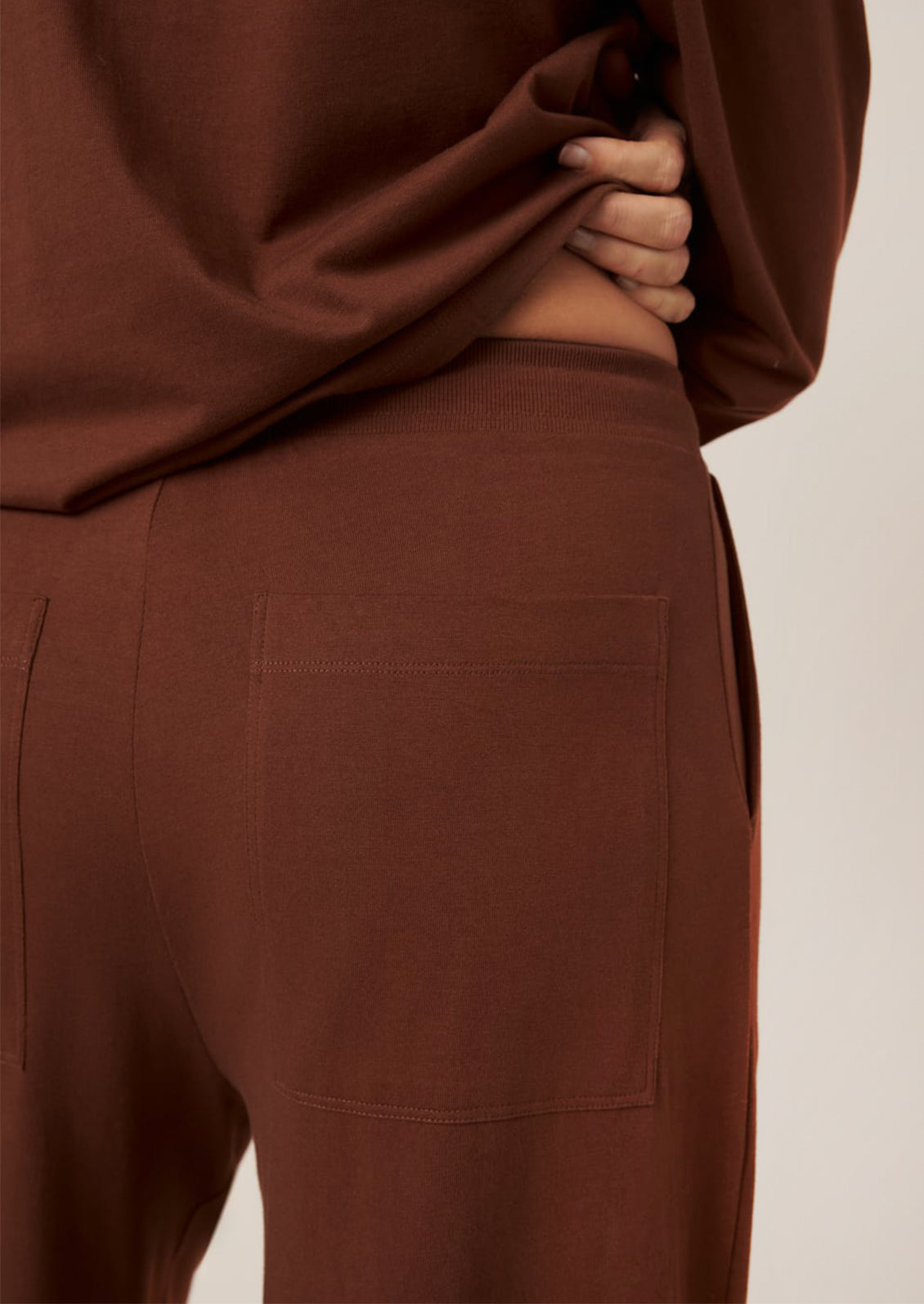 A person wearing a pair of wide leg pants in sequoia brown color.