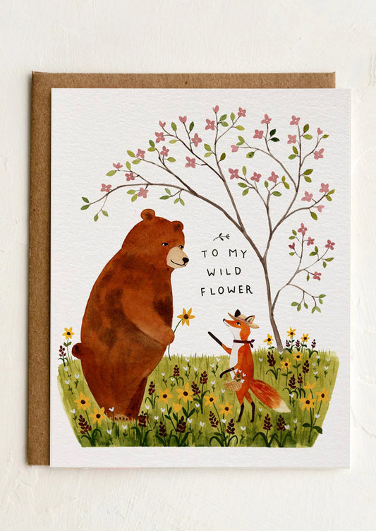 Greeting card with a bear and fox illustration and floral elements.