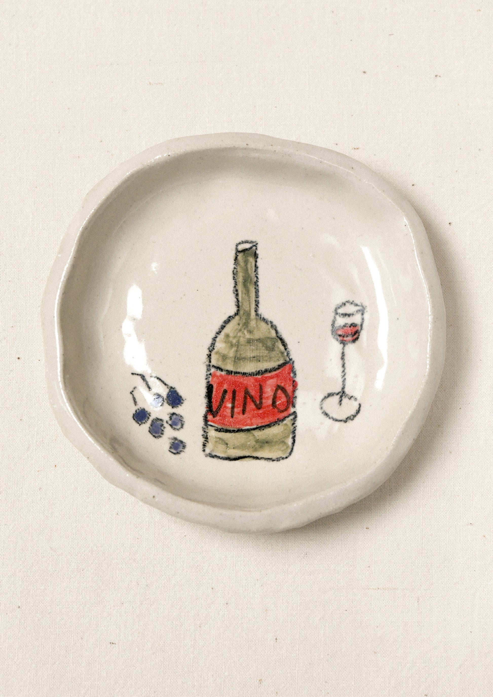 A small ceramic dish with an illustration of wine and grapes.