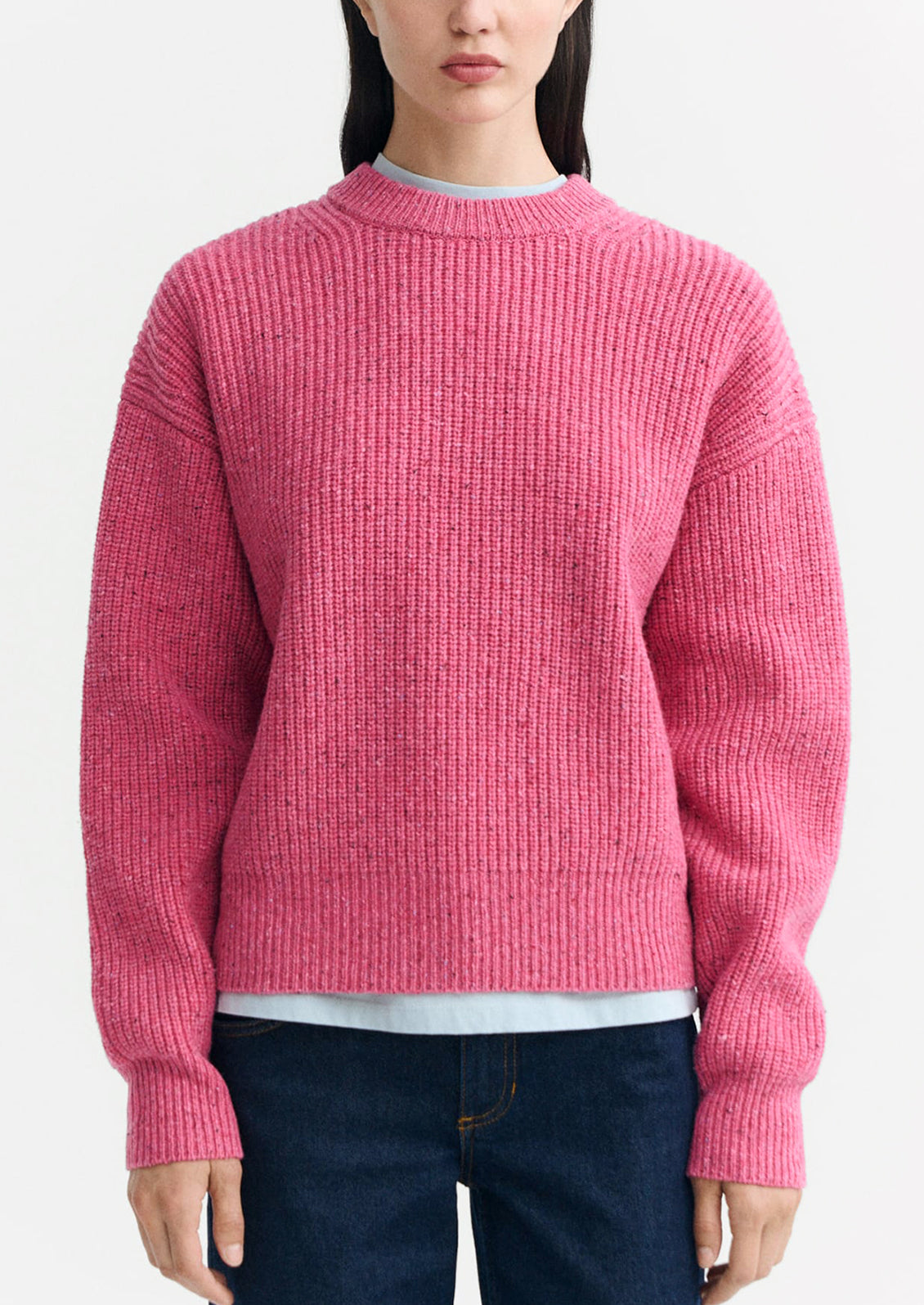 A woman wearing a chunky knit sweater in pink color.