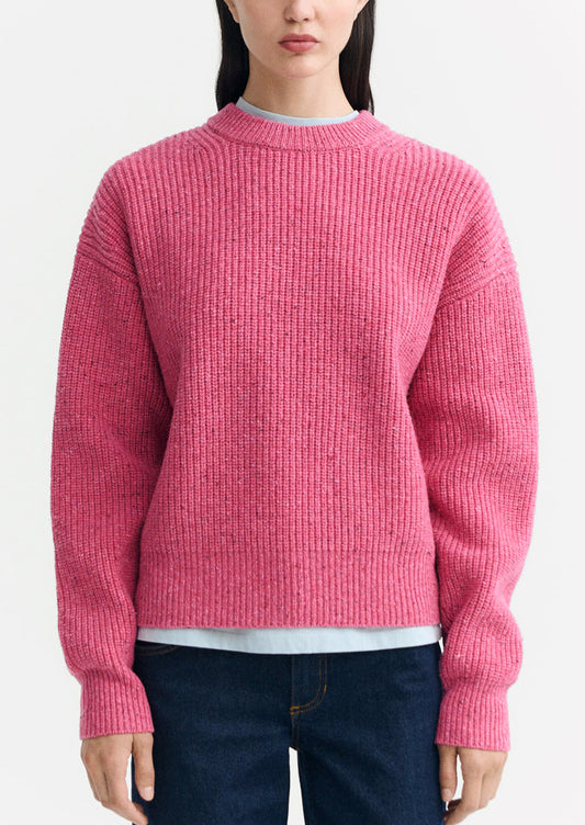 A woman wearing a chunky knit sweater in pink color.