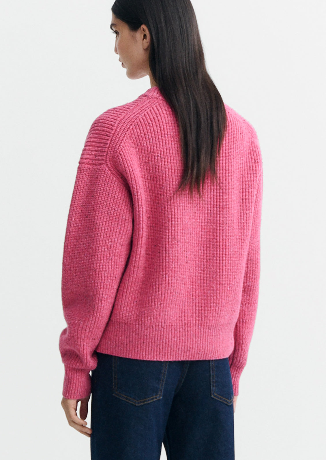 A woman wearing a chunky knit sweater in pink color.