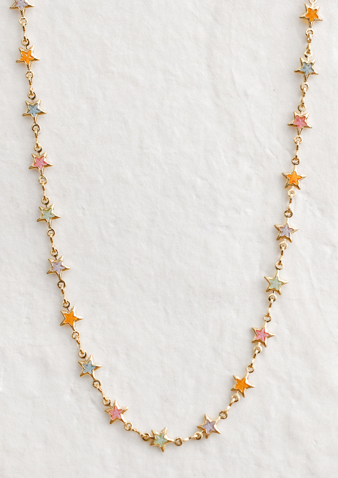 A gold necklace with multicolor pastel star stations.