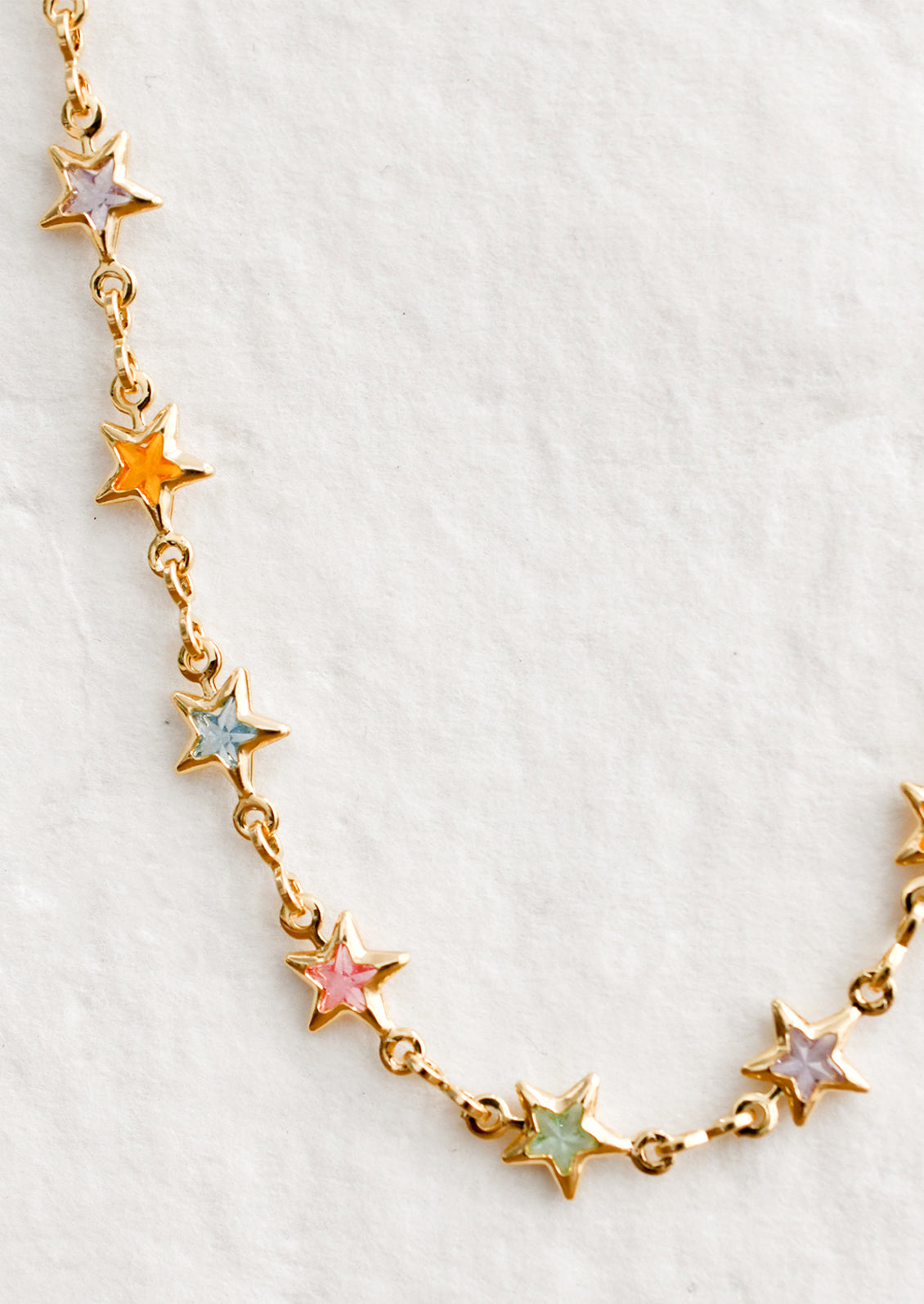 A gold necklace with multicolor pastel star stations.