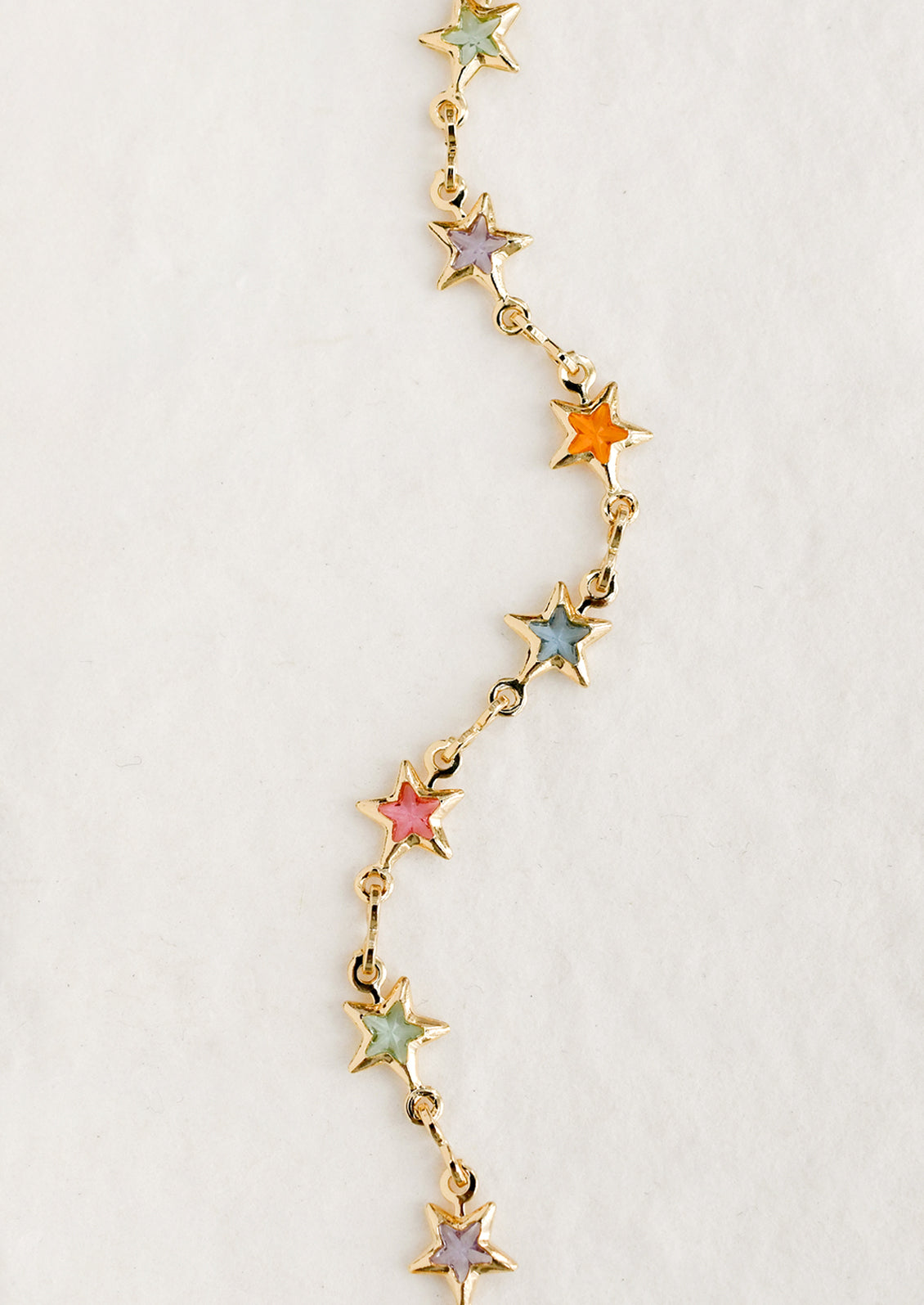 A gold bracelet with pastel colored glass star stations throughout.