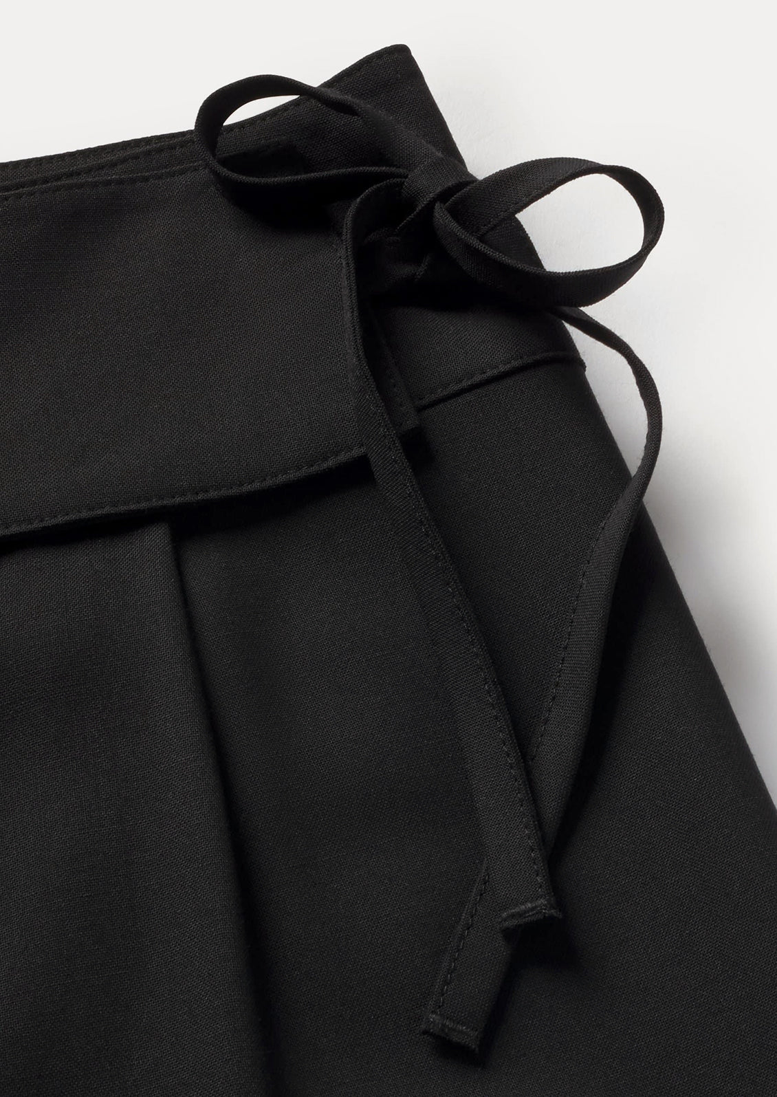 A side tie detail on a pair of black pants.