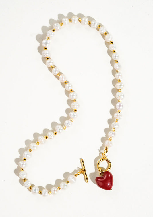 A necklace with alternating gold and pearl beads and red heart toggle clasp.