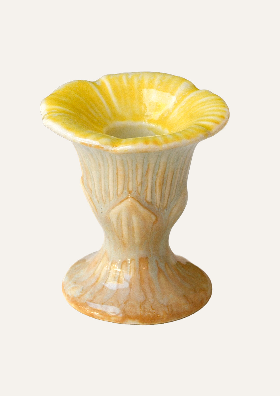 A yellow and peach colored ceramic taper candle holder shaped like a flower.