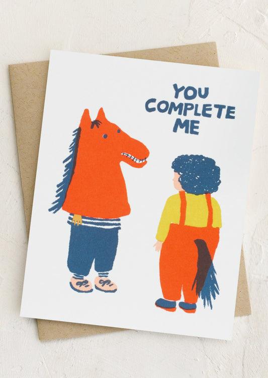 A card with playful illustration reading "You complete me".