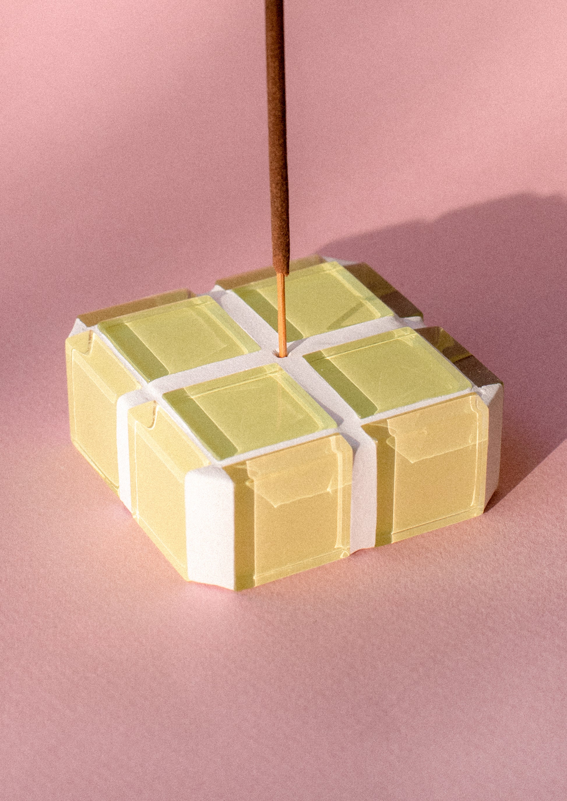 A square cube shape incense holder made up of lemon yellow glass tiles.