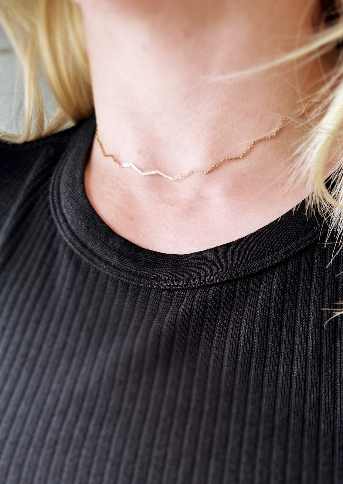 A zig zag gold choker on figure.