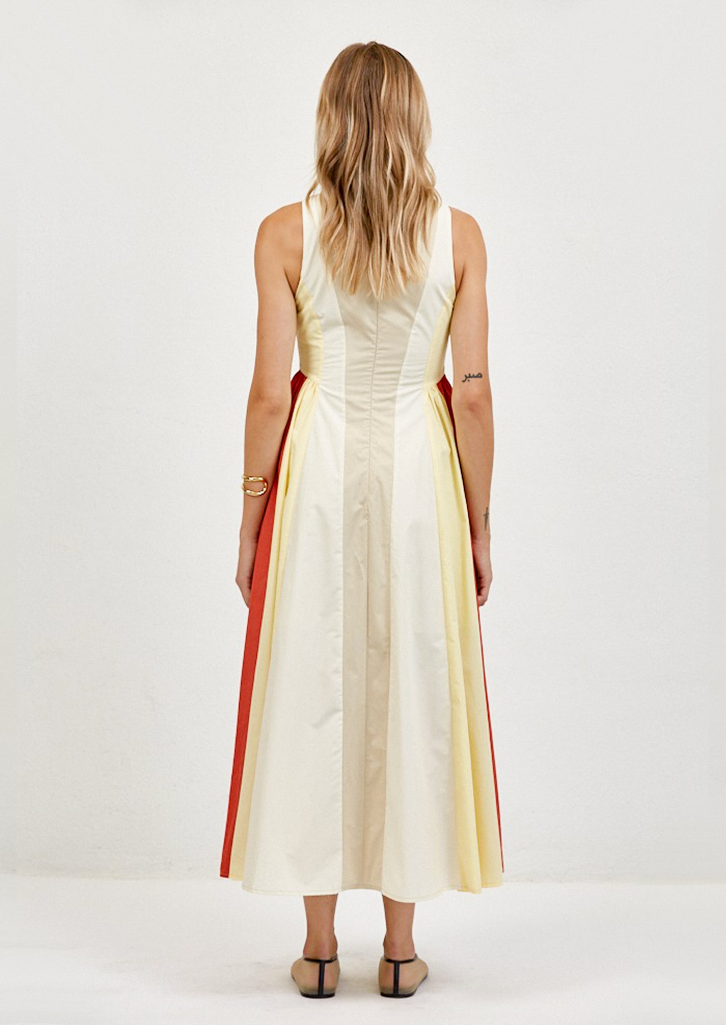 Woman wearing a sleeveless dress with red and yellow stripes on a white background