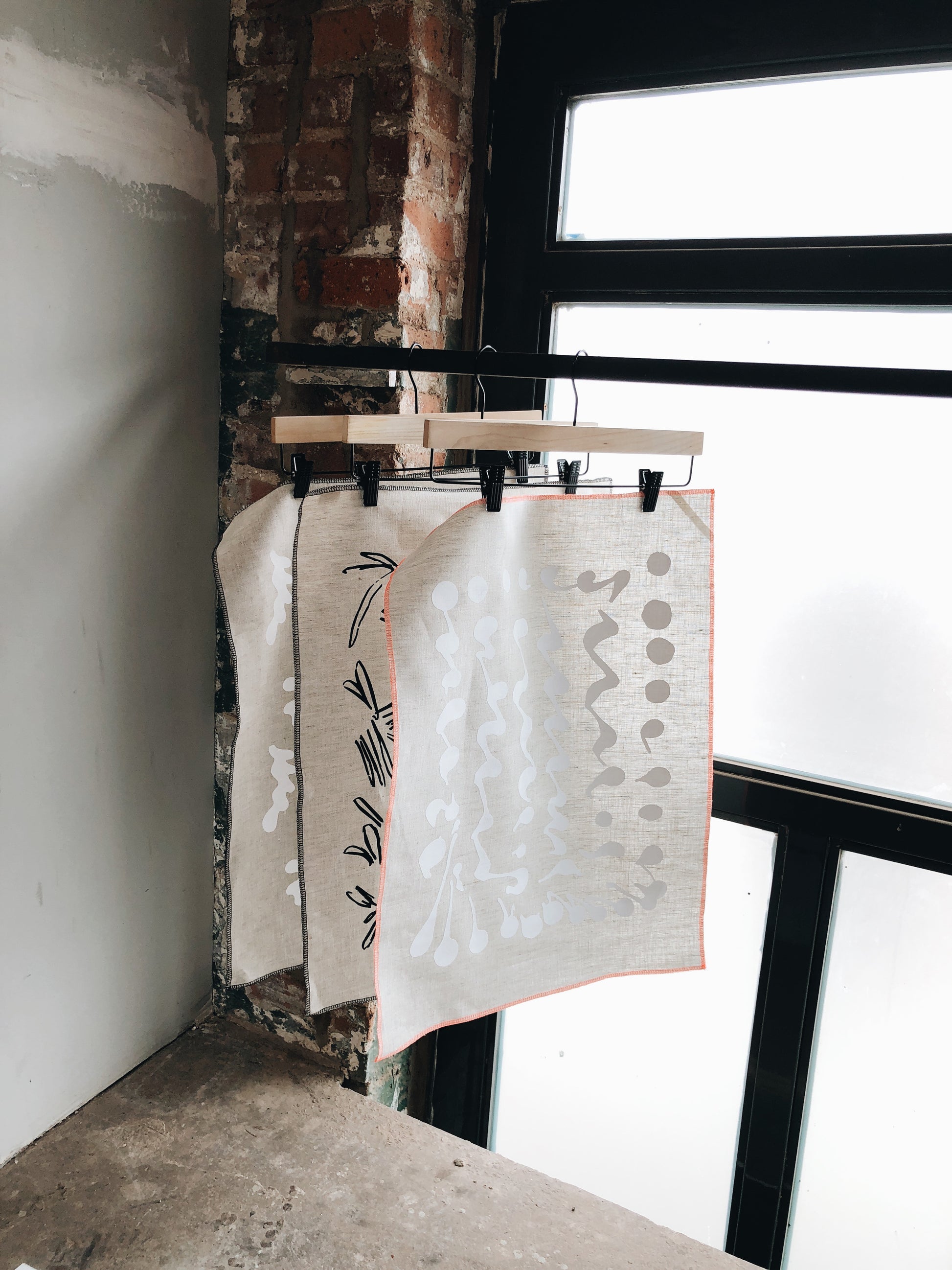 Three Patterned Tea Towels Hanging By A Window - LEIF