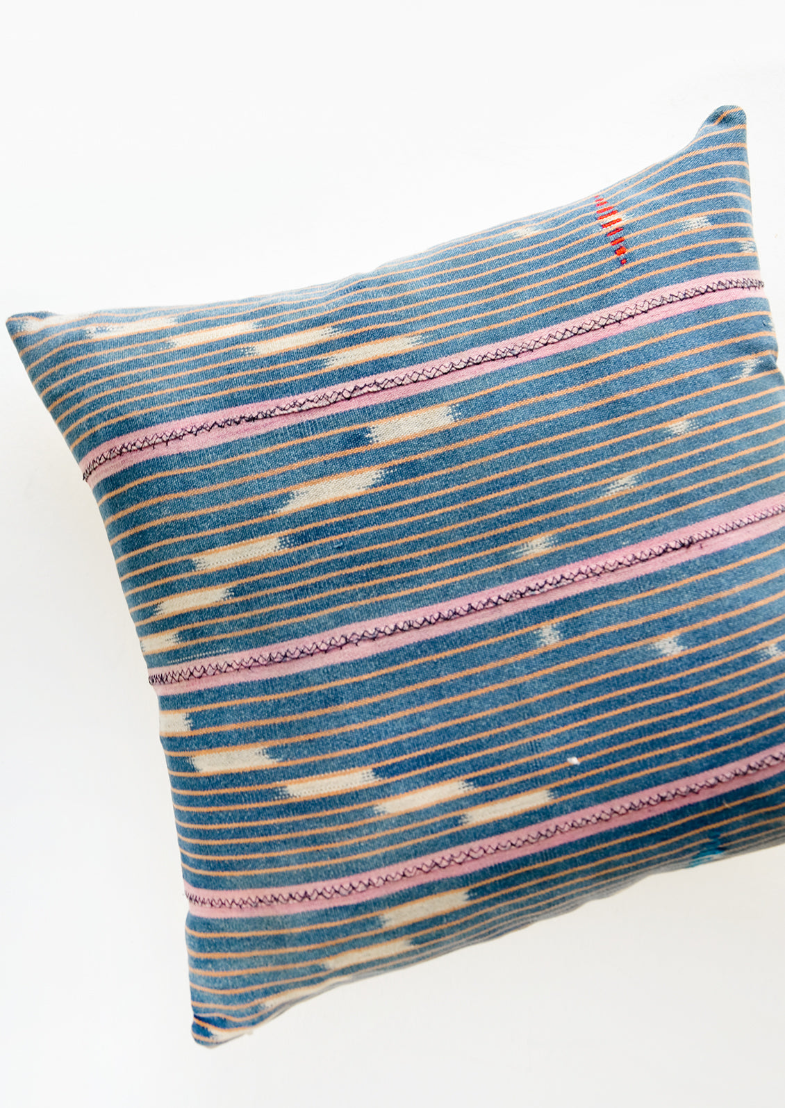 Throw pillow made from vintage indigo Baule fabric with peach and pink stripes