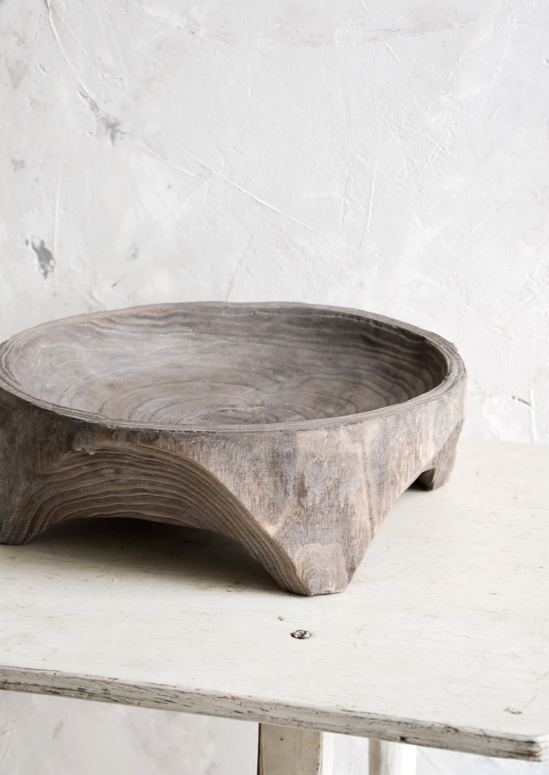 Round, primitive style shallow wooden display bowl with chunky footed base