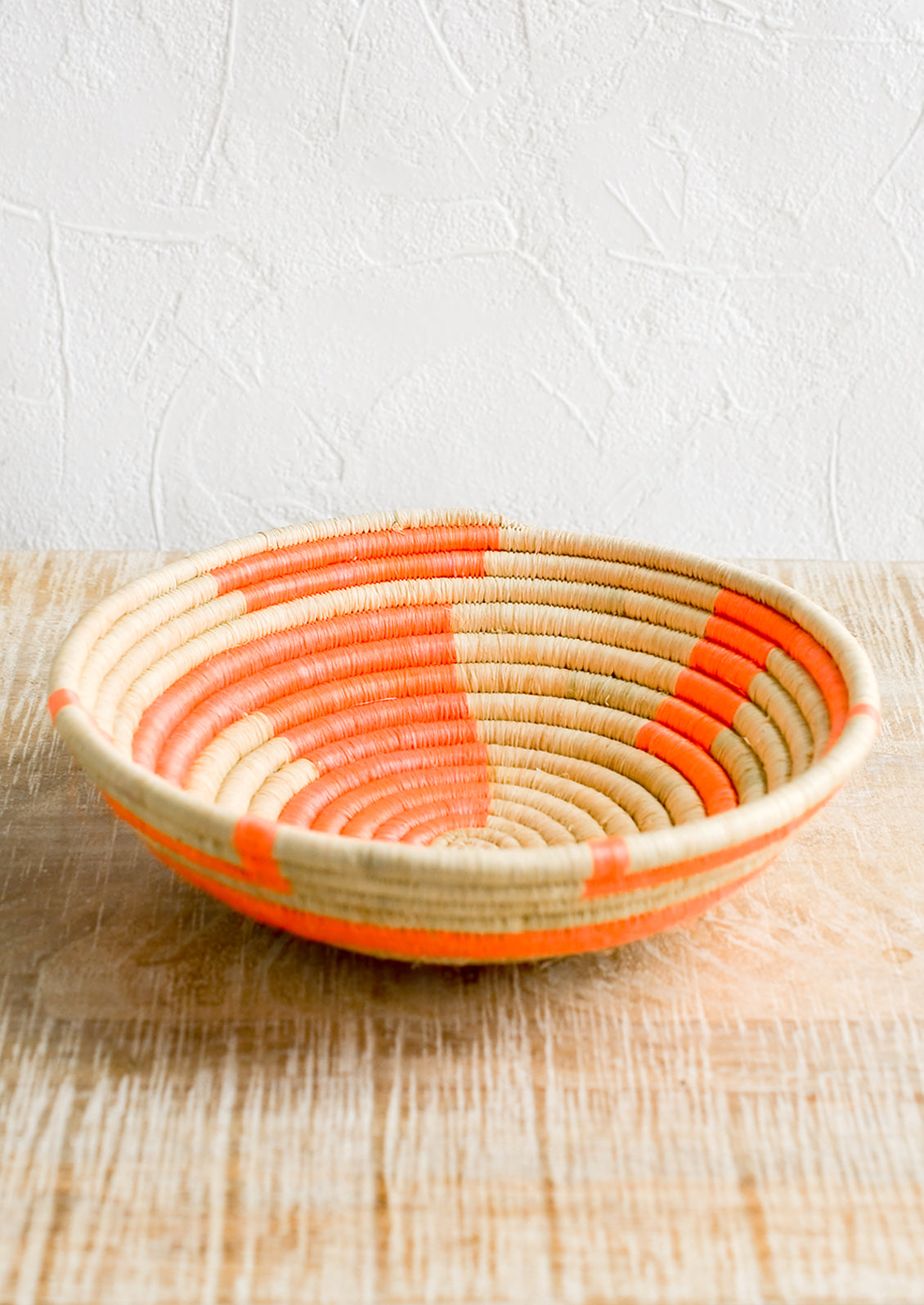 A sweetgrass catchall bowl in tan and neon coral.