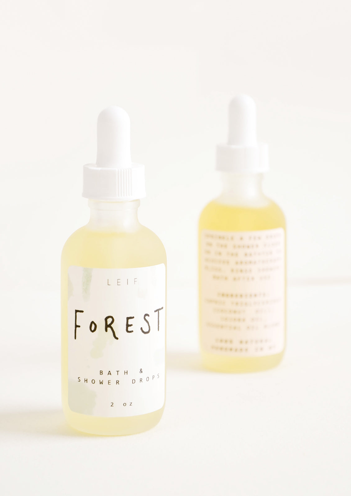 Two frosted glass dropper bottles with white lids and labels.