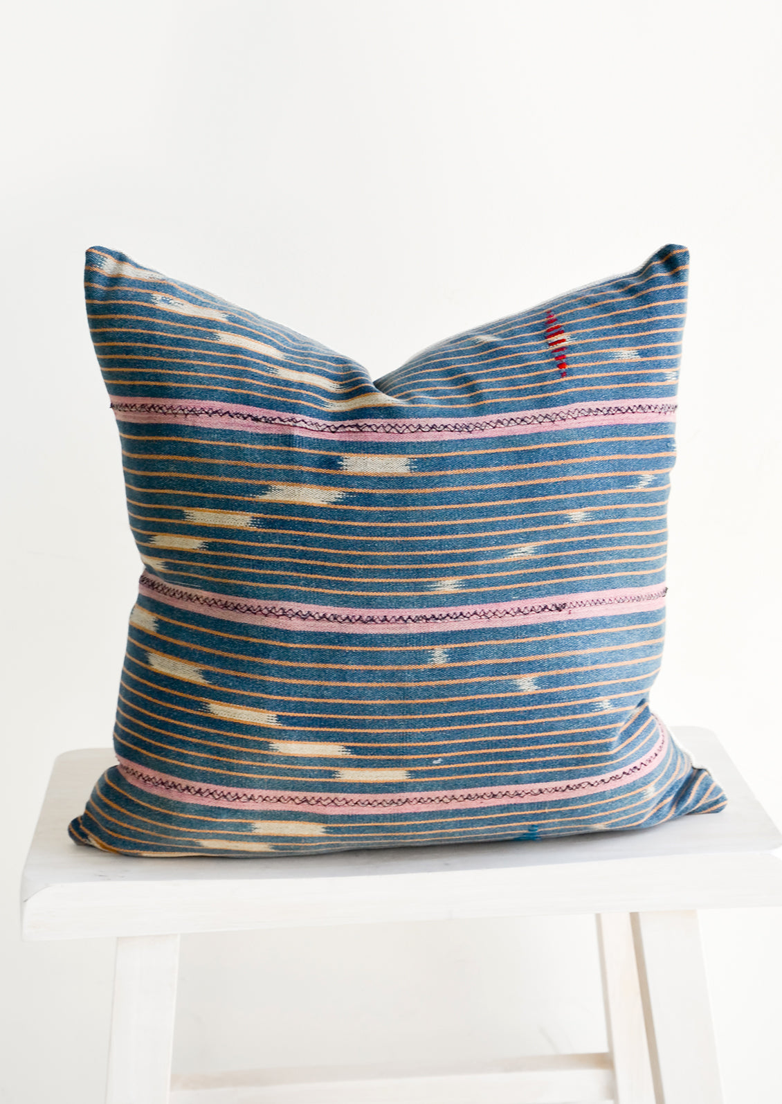 Throw pillow made from vintage indigo Baule fabric with peach and pink stripes
