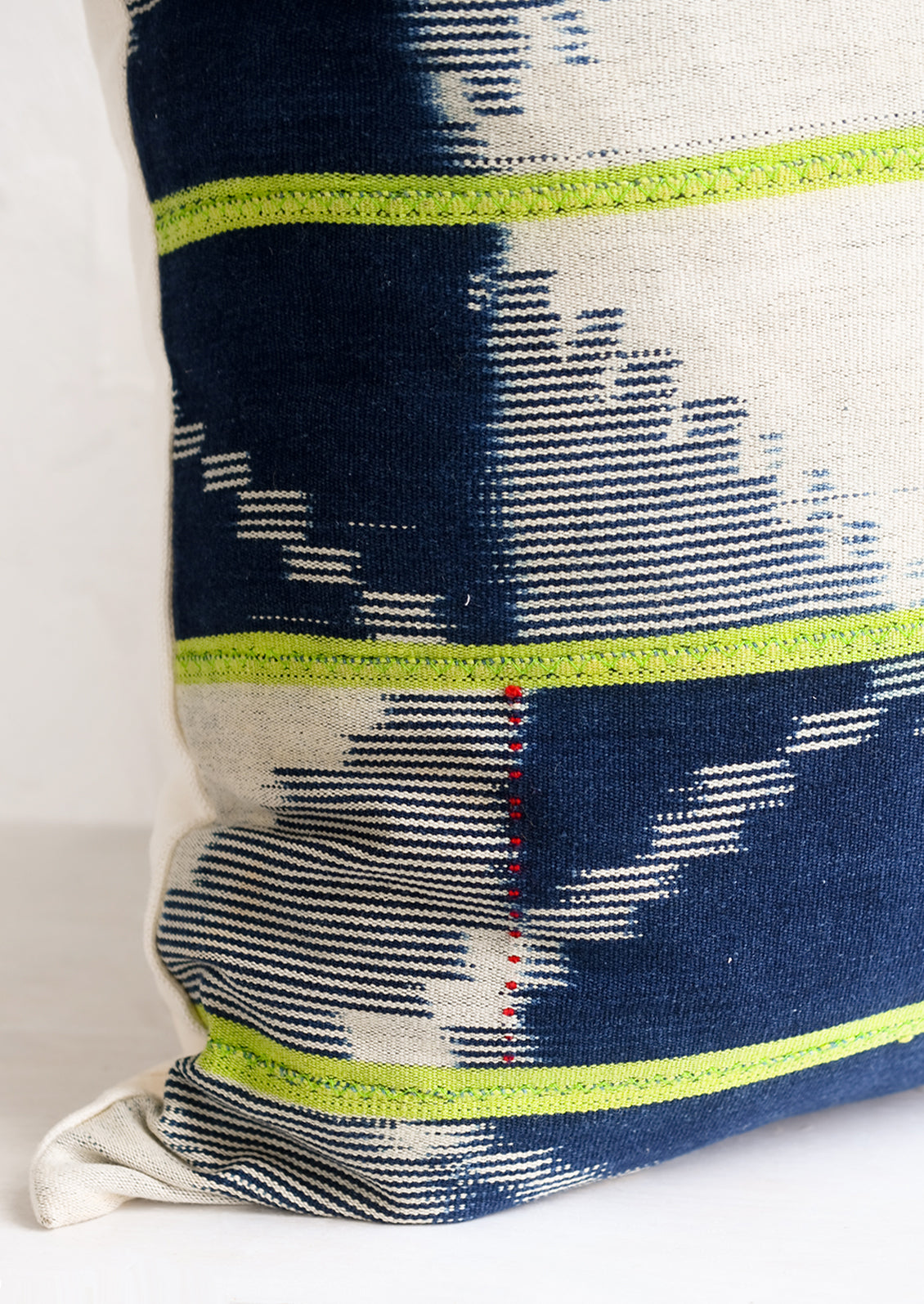 A vintage indigo baule fabric pillow in dark indigo with lime green stripes.