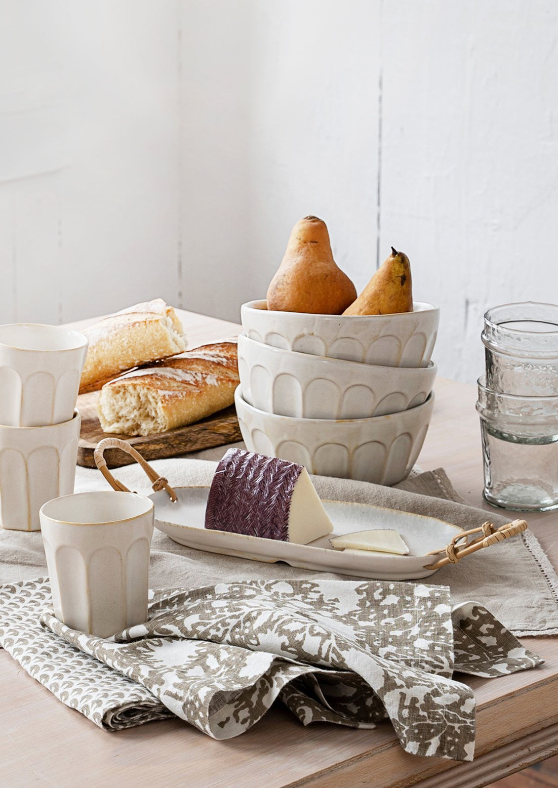 A kitchen scene with ceramics, fruit bread and cheese.