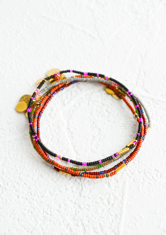 Stack of seed bead bracelets in dark colors with brass accents