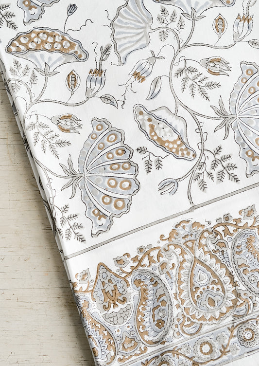 A botanical block printed tablecloth in grey, brown and white.