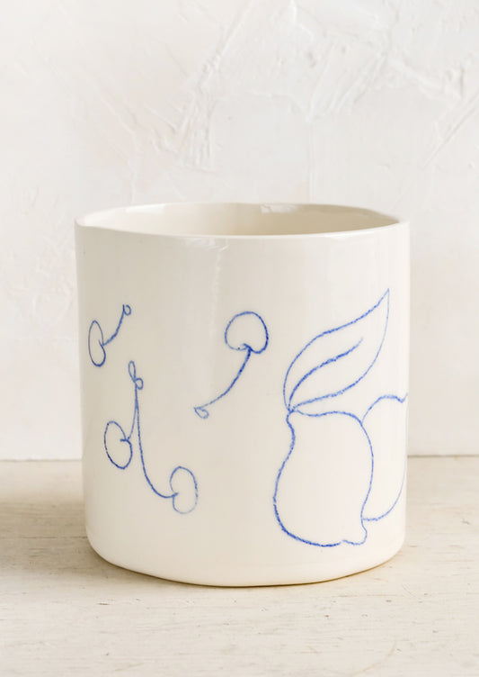 An ivory ceramic planter with fruit line drawings in blue.
