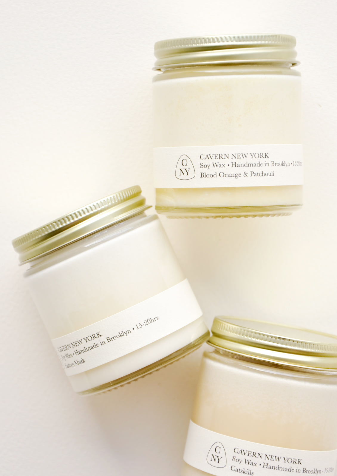 Three white glass jars with gold lids, and white labels with black text