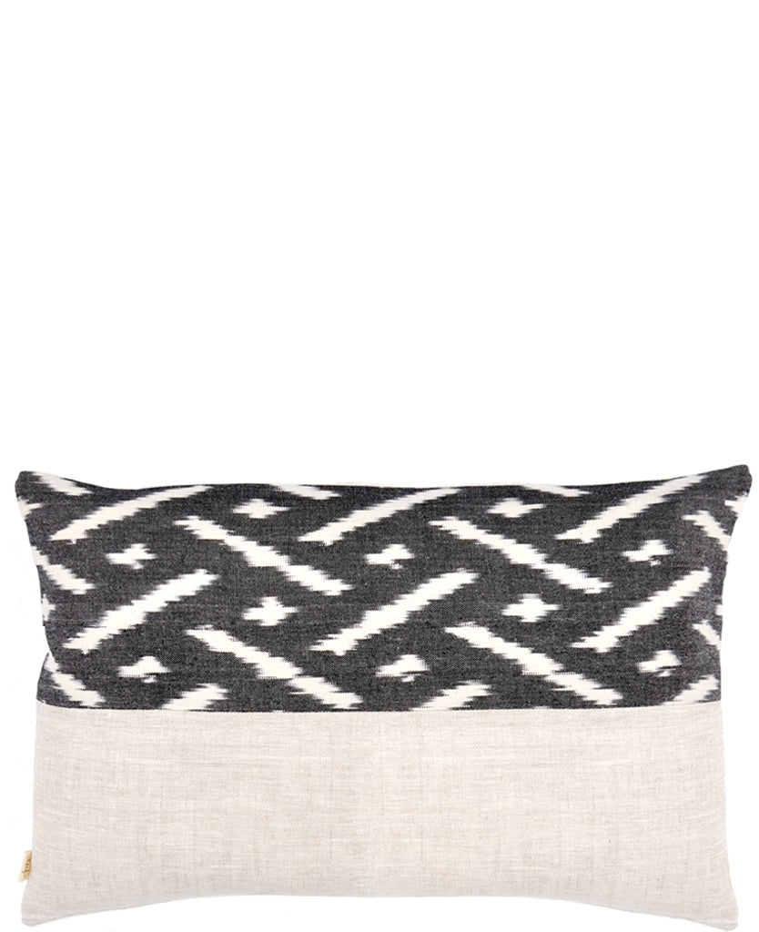 Rectangular throw pillow with black and white ikat patterned top half and natural linen bottom half 