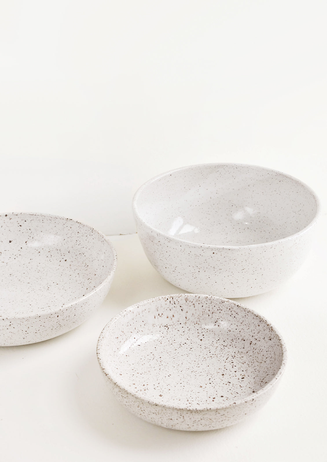 A mix of speckled white ceramic bowls in varied sizes.
