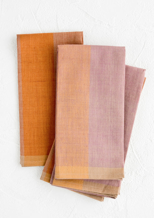 A stack of fabric napkins in purple and orange colorblock design.