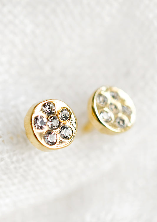 A pair of gold circular stud earrings with embedded clear crystals.