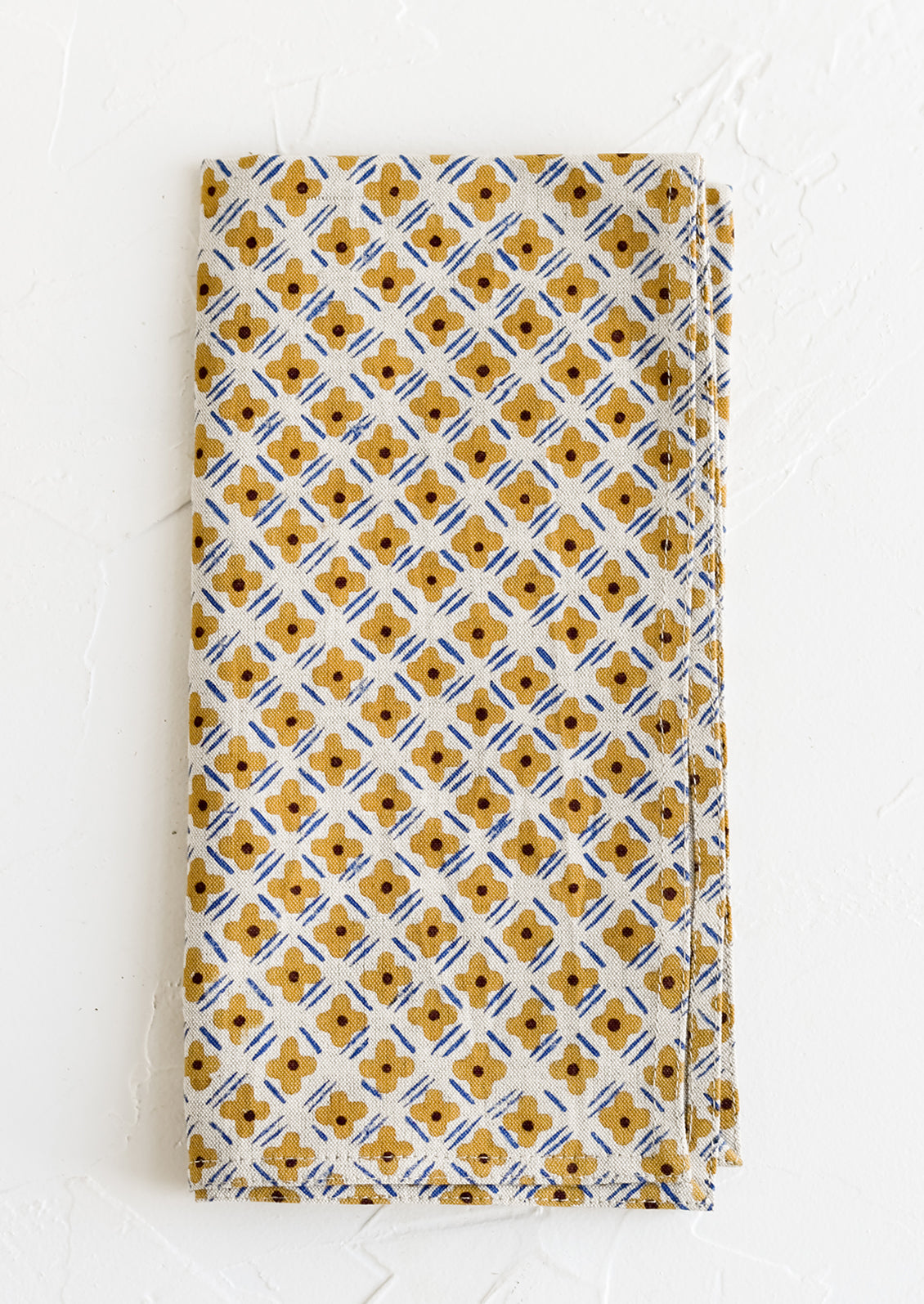 A block printed napkin with ochre and cobalt floral print.