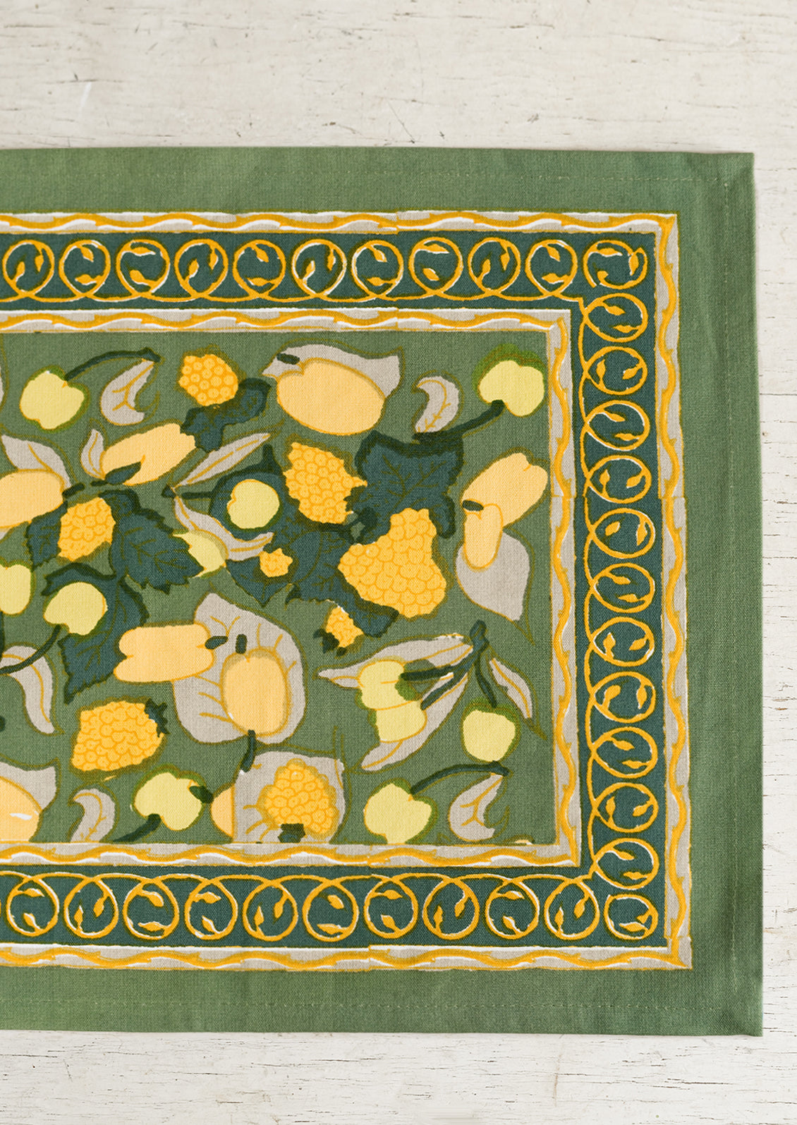 A block printed placemat in green and yellow fruit print.