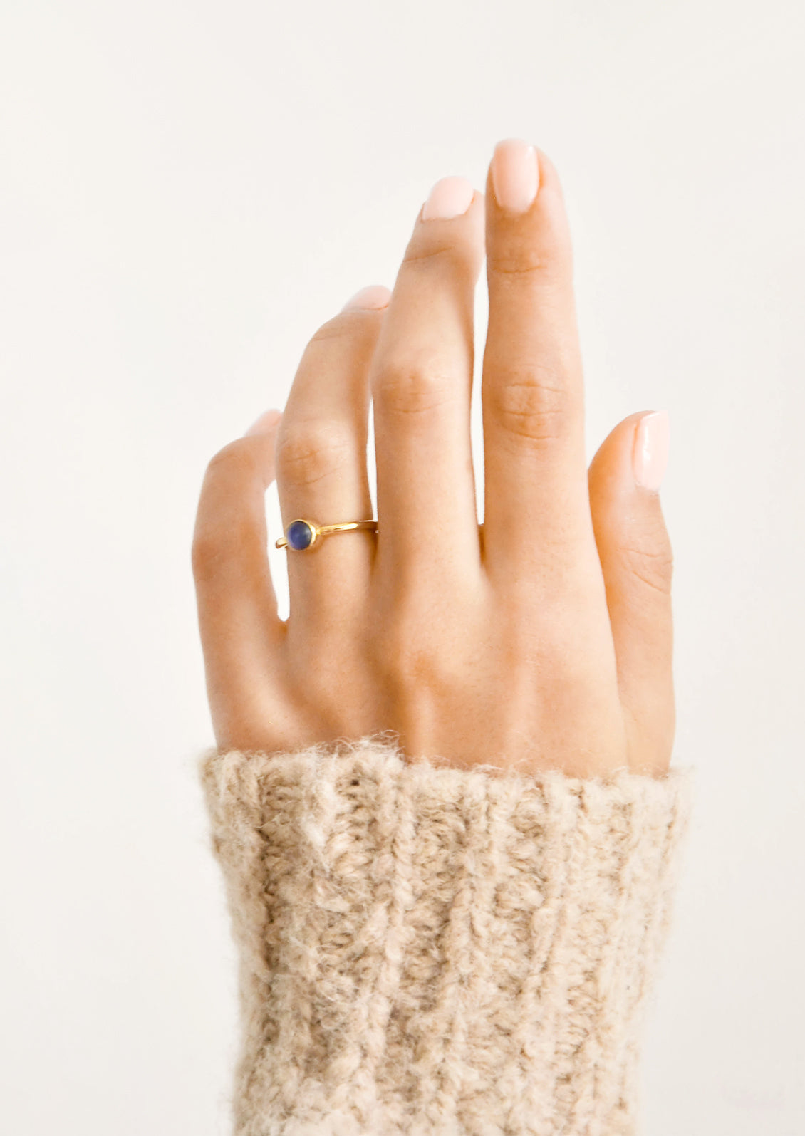 A woman's hand with a blue stone ring on her ring finger.