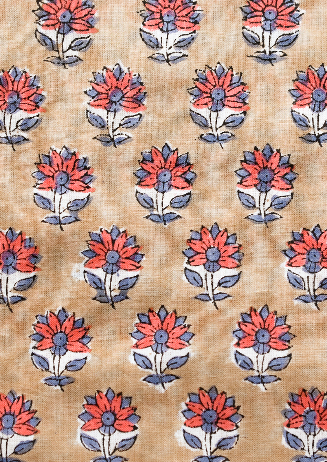 A block printed pillow in light brown with red and dusty blue flower print.