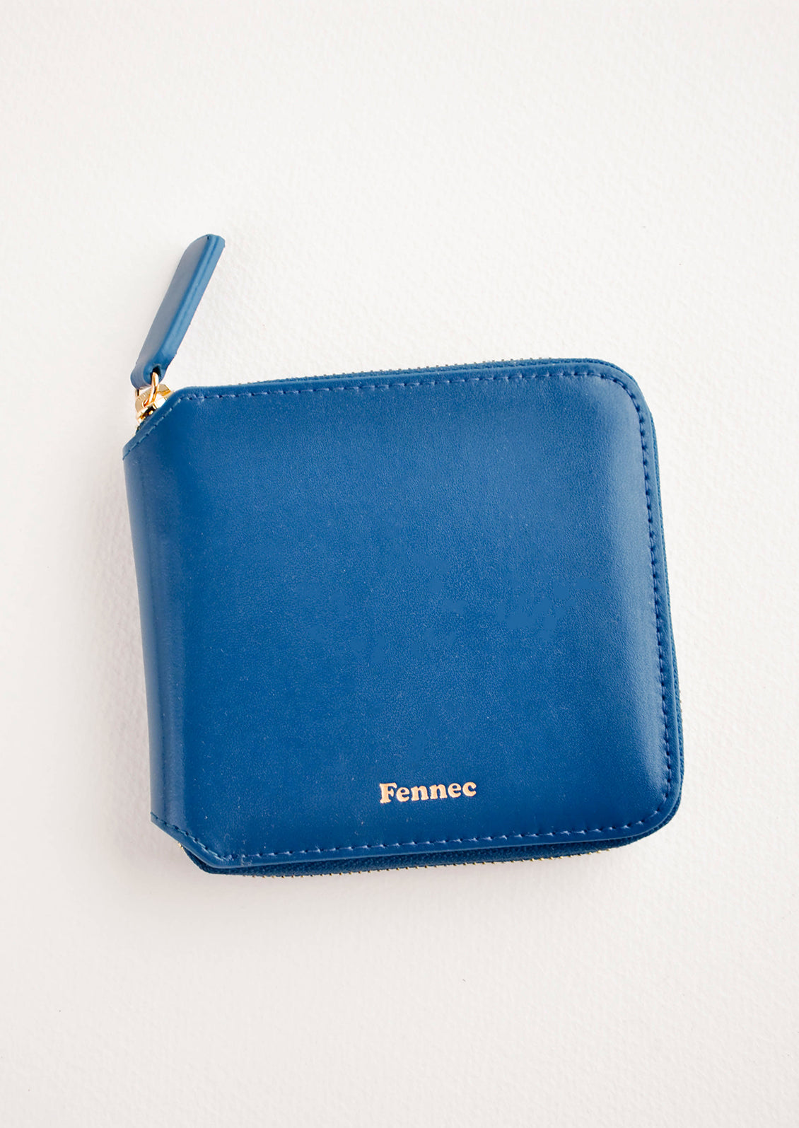 Dark blue leather wallet that zips on three sides, with matching tab pull.