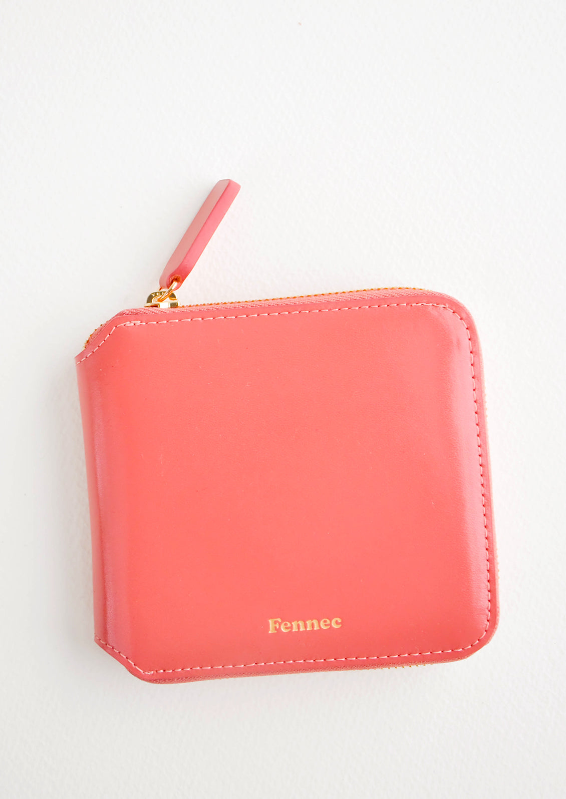 Light red leather wallet that zips on three sides, with matching tab pull.