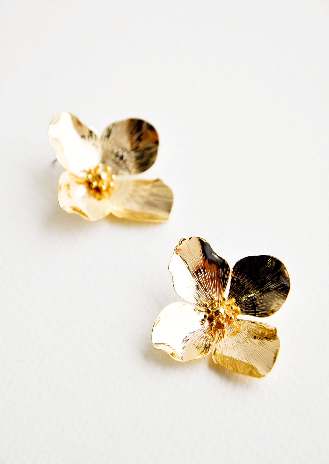 Shiny gold flower shaped earrings with four petals. 