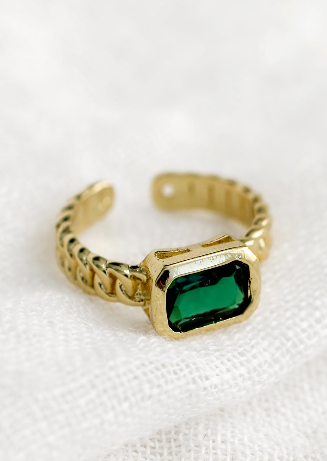 A gemstone ring with heavy chainlink band and rectangular emerald baguette.