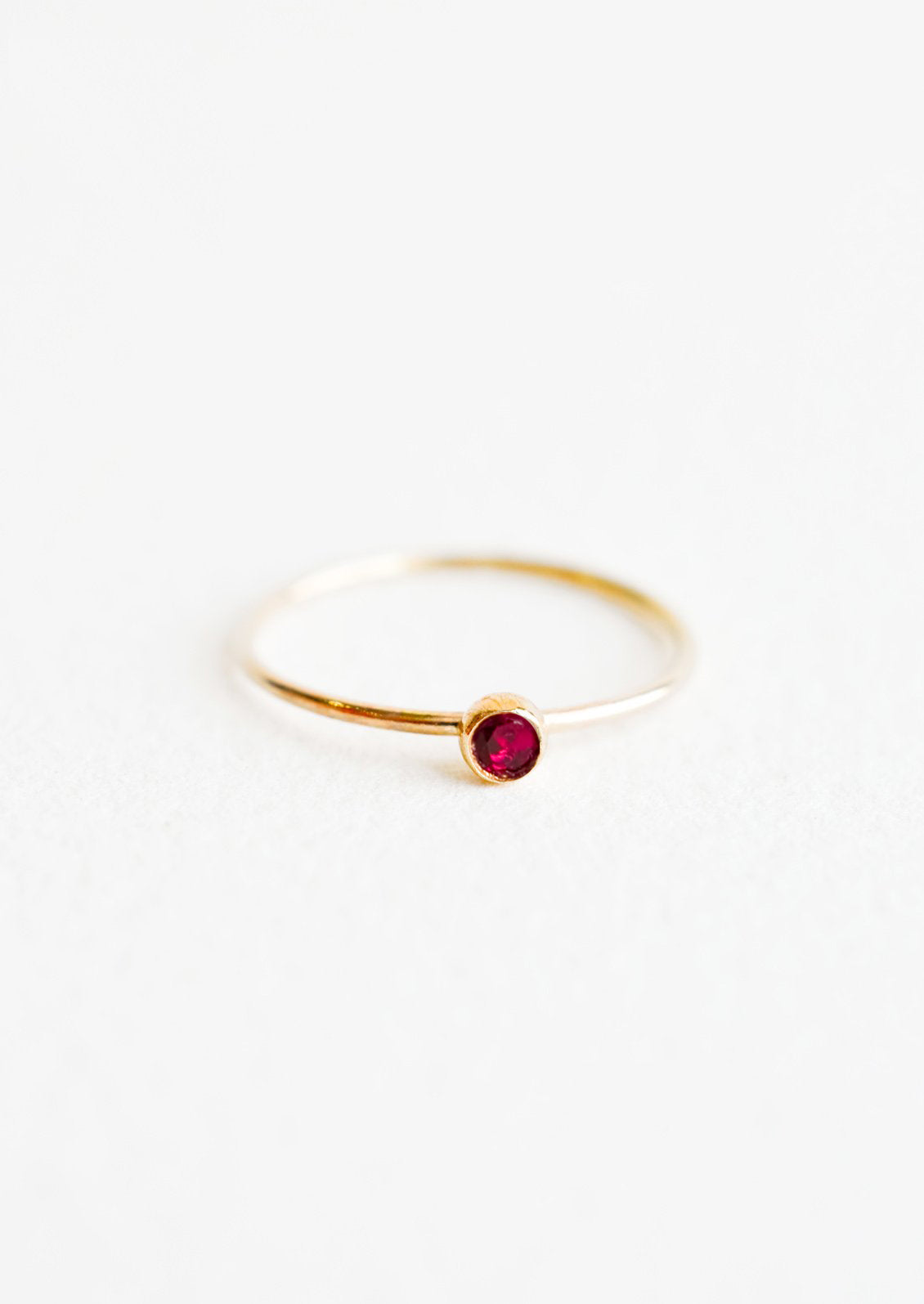 Yellow gold ring with slim band and small red garnet stone.