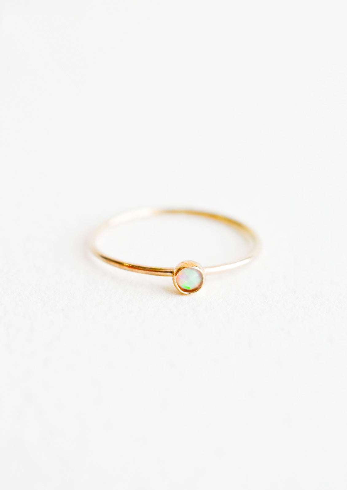 Yellow gold ring with slim band and small white opal stone.