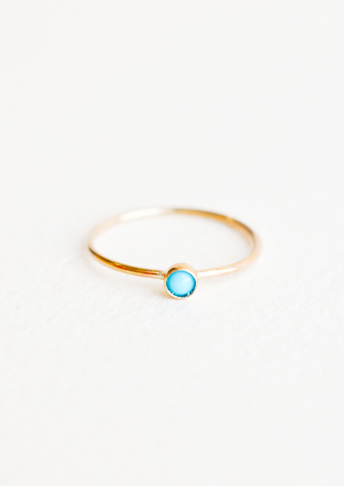 Yellow gold ring with slim band and small blue turquoise stone.