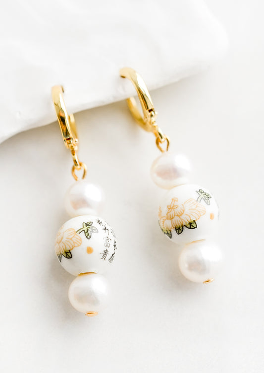A pair of pearl earrings with gold huggie hoop clasp and Chinese ceramic beads.